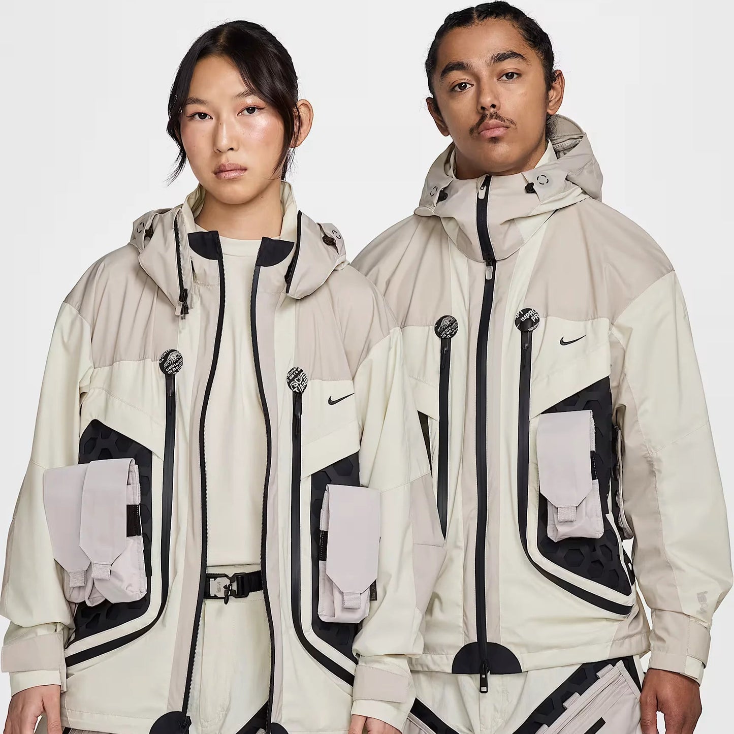 Models showcasing the Nike ISPA Butterfly Jacket in white and beige, highlighting its versatile modular build, utility pockets, and innovative street-inspired design.