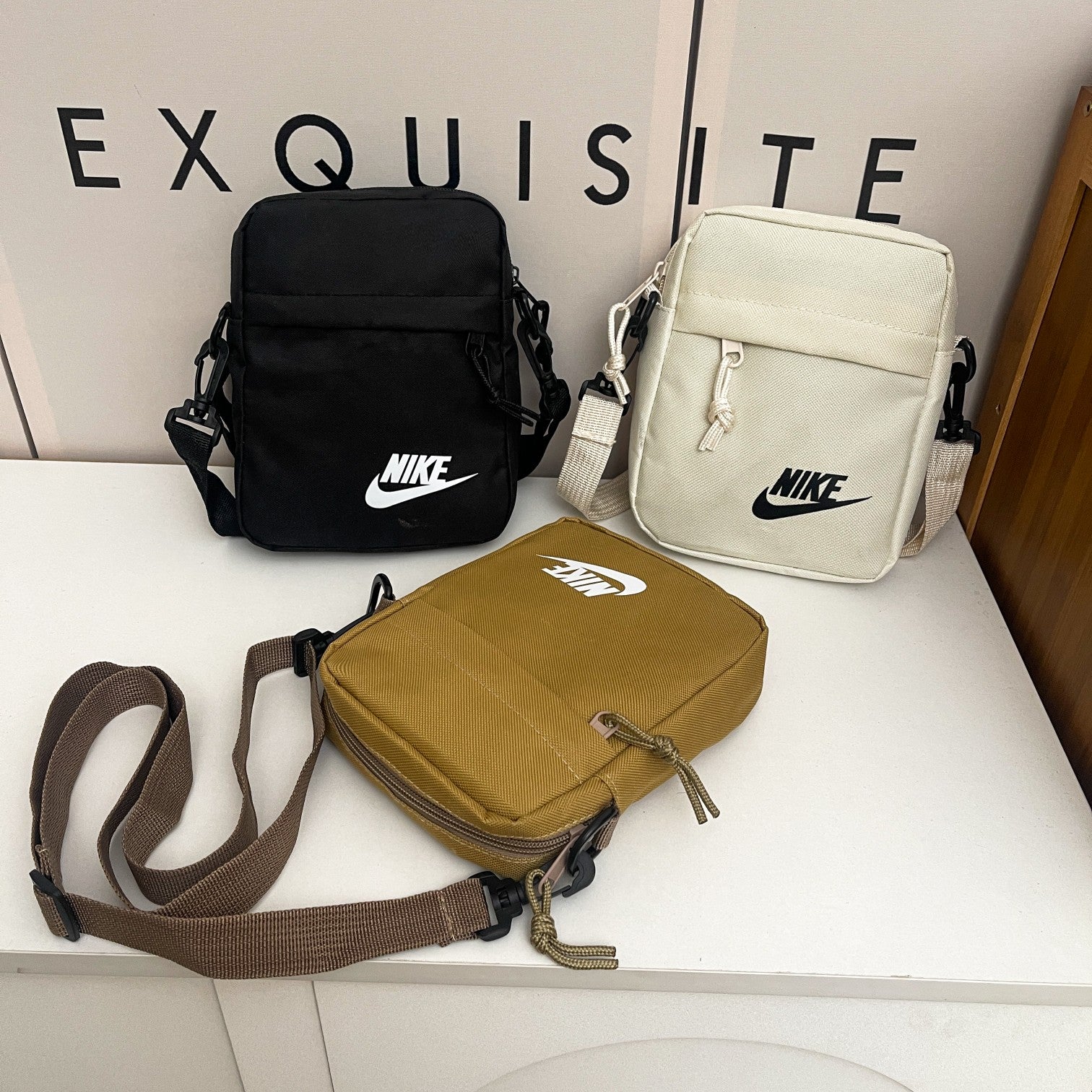 Nike compact crossbody shoulder bags in black, cream, and khaki colors featuring adjustable straps, zip compartments, and the classic Nike logo, designed for everyday carry.
