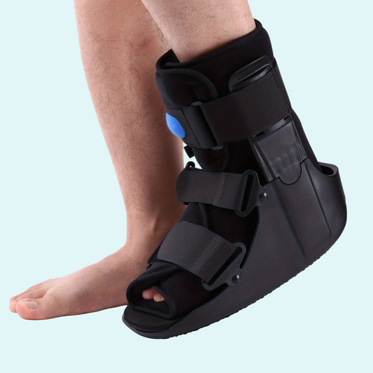 Orthopedic walking boot for foot or ankle injuries, shown on a right leg.
Features a black hard-shell frame with open toe and rocker bottom sole.
Three adjustable Velcro straps ensure a secure, customized fit.
Built-in air bladder with visible blue valve provides extra compression.
Ideal for fractures, sprains, post-surgery recovery, and immobilization.