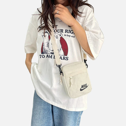 Nike compact crossbody shoulder bags in black, cream, and khaki colors featuring adjustable straps, zip compartments, and the classic Nike logo, designed for everyday carry.