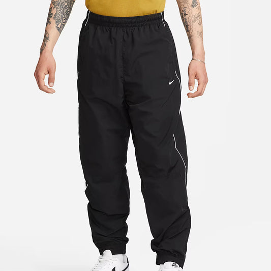 Nike Solo Swoosh Men’s Track Pants in black, front view. Features elastic waistband, side pockets, relaxed fit and reflective piping for modern athletic style.