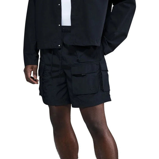 Man in Nike Tech Woven Cargo Shorts in black, featuring a minimalist design with utility pockets, perfect for versatile casual and streetwear looks.